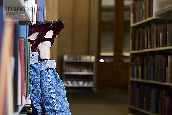 Studentin in einer öffentlichen Bibliothek  Füße hoch