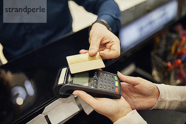 Nahaufnahme eines bargeldlos mit Kreditkarte zahlenden Kunden in einem Geschäft