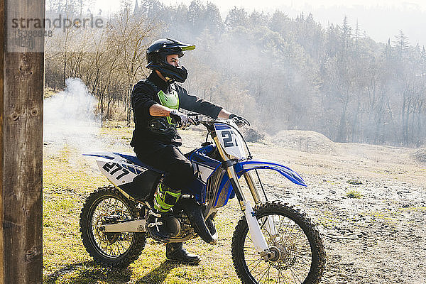 Motocross-Fahrer auf Motorrad mit aus dem Auspuffrohr austretendem Rauch