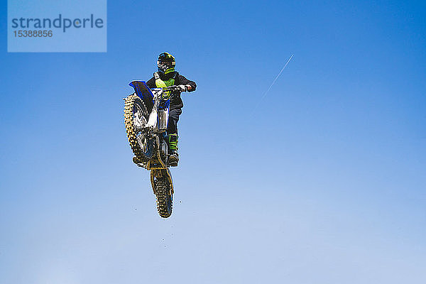 Motocross-Fahrer springt bei blauem Himmel