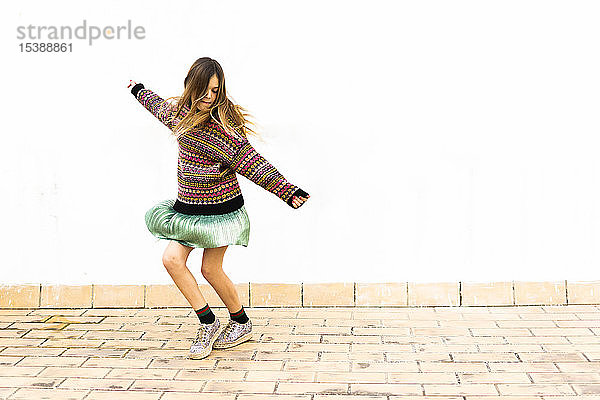 Mädchen tanzt vor einer weißen Wand