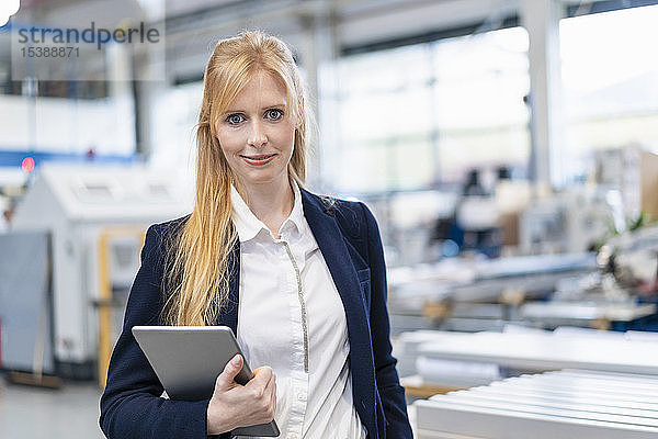 Porträt einer selbstbewussten Geschäftsfrau mit Tablette in der Fabrik