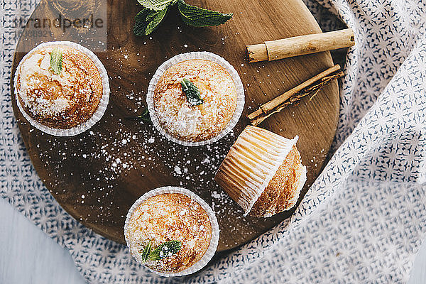 Selbstgebackene Muffins mit Zimt und Minze auf Holzbrettchen