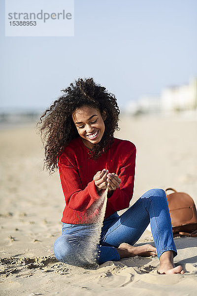 Glückliche junge Frau sitzt am Strand