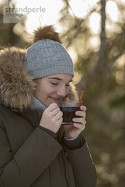 Porträt einer jungen Frau  die im Winter eine Tasse Tee genießt
