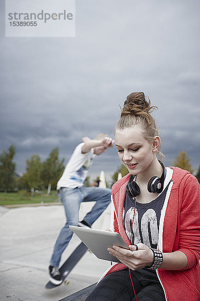 Teenager-Mädchen benutzt Tablette in einem Skatepark