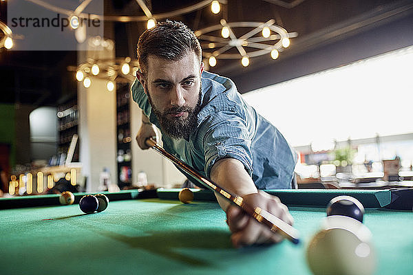 Porträt eines konzentrierten Mannes beim Billardspielen