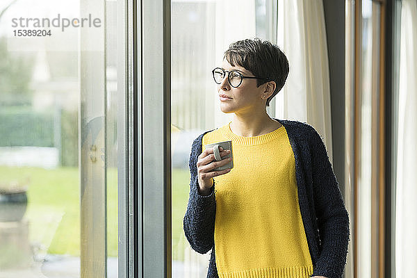 Bildnis einer Frau mit einer Tasse Kaffee  die aus dem Fenster schaut