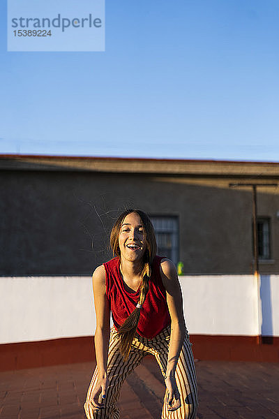 Porträt eines glücklichen Teenager-Mädchens auf der Dachterrasse bei Sonnenuntergang