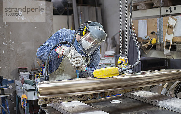 Kunstgiesserei  Giessereiarbeiter beim Polieren von Metall