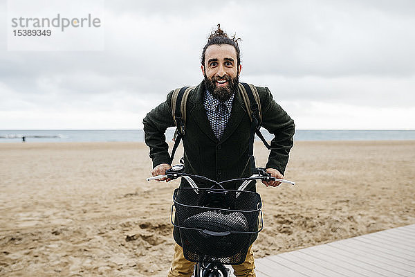 Porträt eines glücklichen Mannes mit E-Bike am Strand