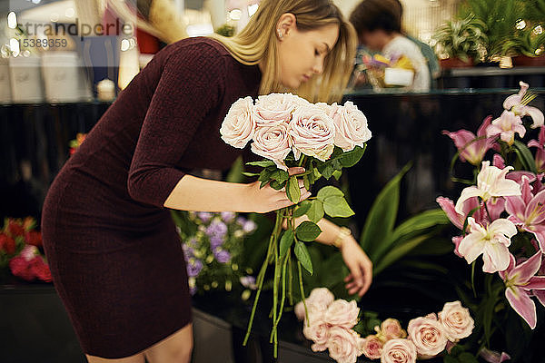 Frau arrangiert Blumen im Blumenladen