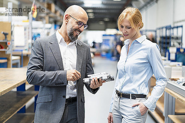 Geschäftsmann und Geschäftsfrau untersuchen Werkstück in Fabrik