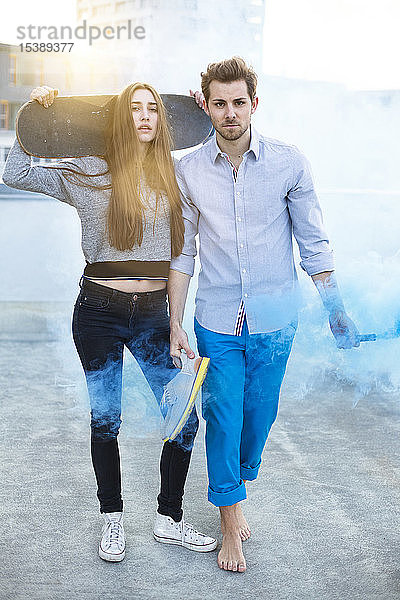 Porträt eines jungen Paares Rauchfackel und Skateboard