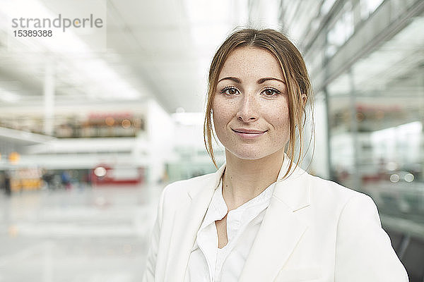 Porträt einer lächelnden jungen Geschäftsfrau am Flughafen