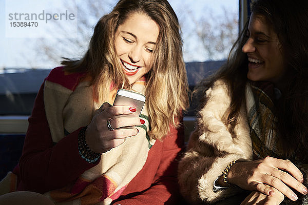 Großbritannien  London  zwei glückliche Frauen in U-Bahn-Zug mit Mobiltelefon