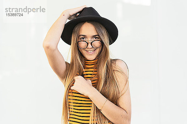 Porträt einer glücklichen Teenagerin mit Hut und Brille