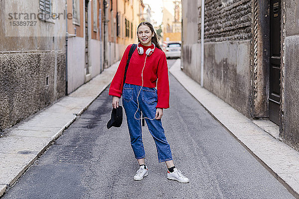 Junge Frau mit rotem Pullover und Kopfhörern in Verona