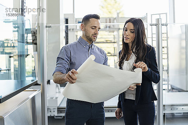 Geschäftsmann und Geschäftsfrau besprechen Plan in moderner Fabrik