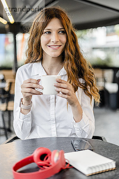 Junge Geschäftsfrau sitzt im Café  arbeitet und trinkt Kaffee