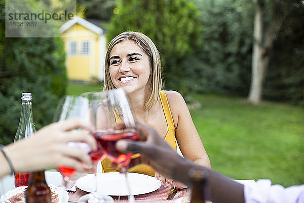 Freunde stoßen mit Wein an ata Sommerabendessen im Garten