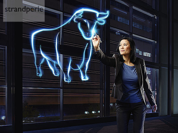 Geschäftsfrau malt einen Stier mit Licht