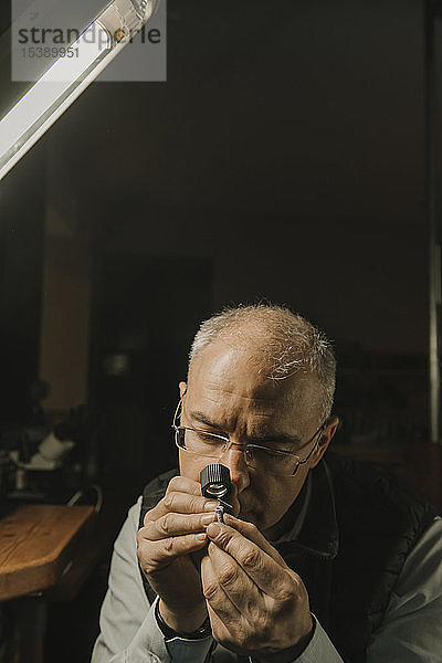 Kunsthandwerker betrachtet Ring mit Edelstein  Porträt