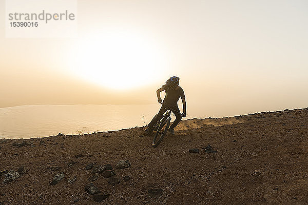 Spanien  Lanzarote  Mountainbiker auf einer Fahrt an der Küste bei Sonnenuntergang