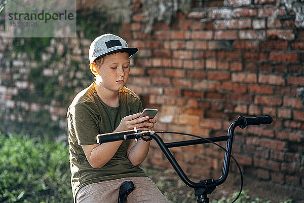 Junge mit bmx-Fahrrad mit Handy