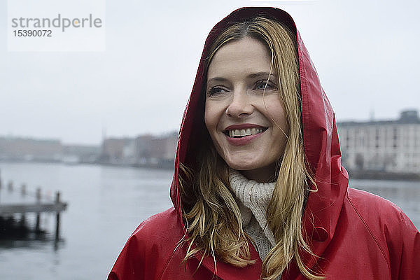 Dänemark  Kopenhagen  Porträt einer glücklichen Frau an der Uferpromenade bei Regenwetter