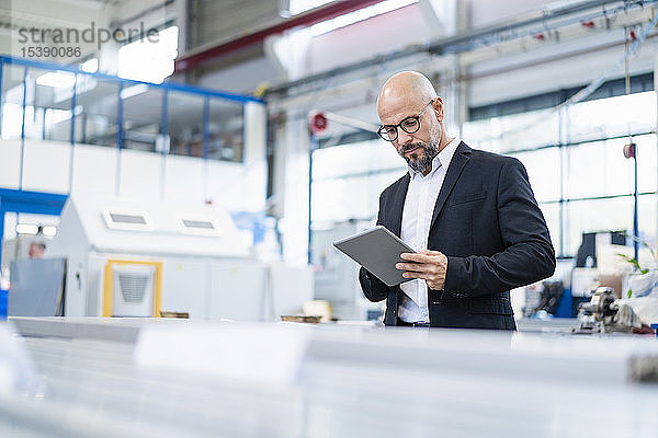 Geschäftsmann mit Tablette in der Fabrik