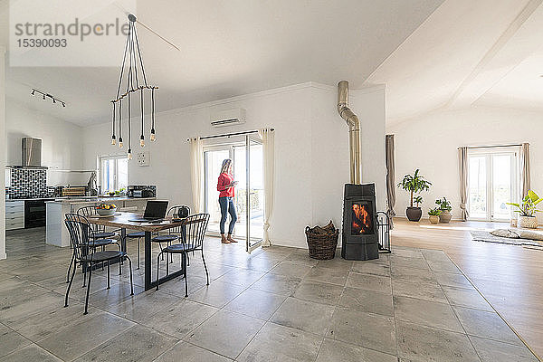 Frau steht im Türrahmen eines modernen Wohnzimmers mit Kamin