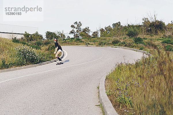 Spanien  Teenagerin auf Skateboard eine Straße entlang