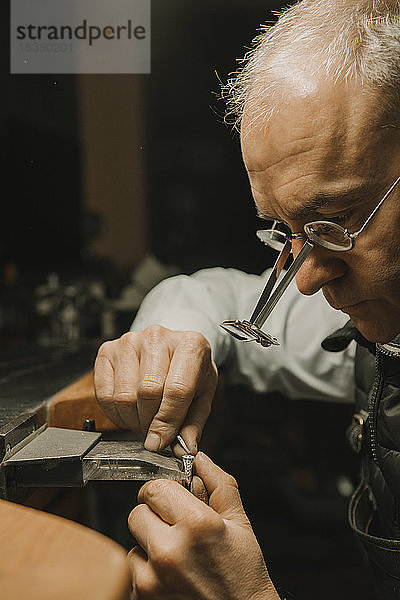 Kunsthandwerker  der in seiner Werkstatt Schmuck herstellt