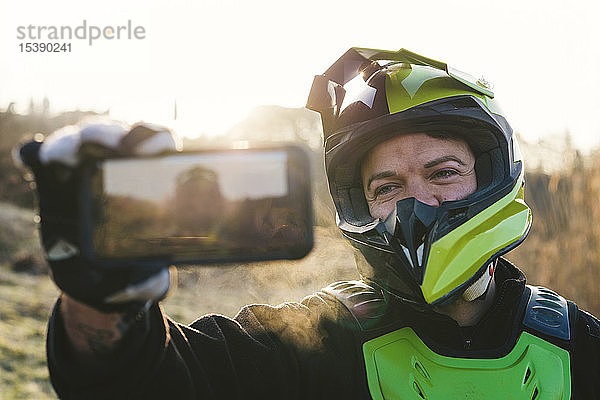 Porträt eines Motocross-Fahrers  der bei Sonnenuntergang ein Selfie macht