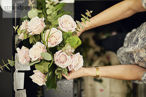 Nahaufnahme eines Floristen beim Arrangieren von Blumen im Blumengeschäft