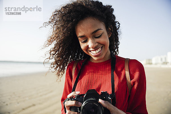 Lächelnde junge Frau schaut in die Kamera am Strand