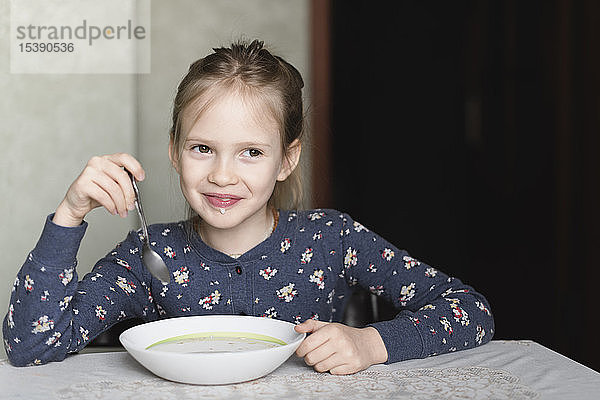 Porträt eines lächelnden kleinen Mädchens beim Essen von Hafermehl
