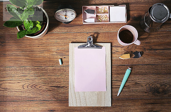 Klemmbrett mit rosa Blankopapier  Kaffeetasse und anderen Utensilien auf dem Schreibtisch im Heimbüro  Draufsicht