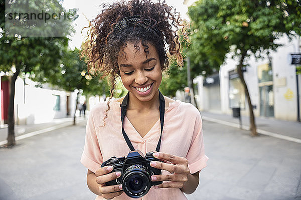 Lächelnde junge Frau schaut in der Stadt in die Kamera