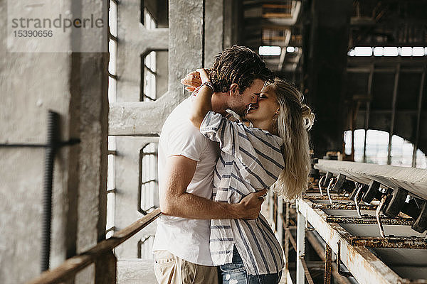 Junges Paar küsst sich in einem alten Bahnhof