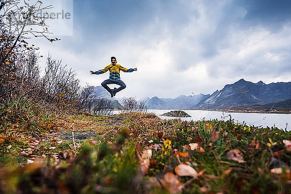 Norwegen  Lofoten  Mann springt an die Küste