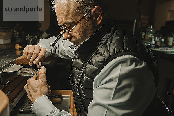 Kunsthandwerker  der in seiner Werkstatt Schmuck herstellt