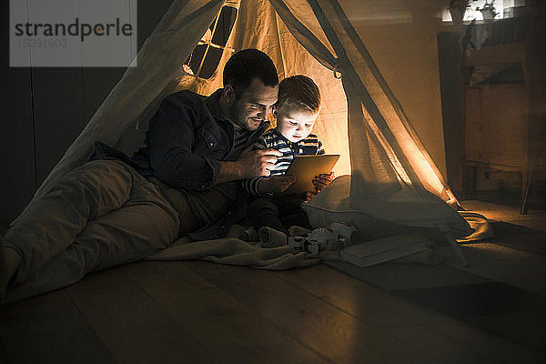 Vater und Sohn teilen sich eine Tafel in einem dunklen Zelt zu Hause