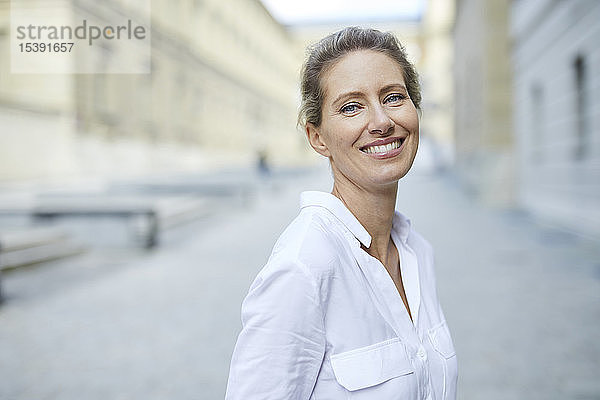 Porträt einer lächelnden Frau mit weißem Hemd in der Stadt