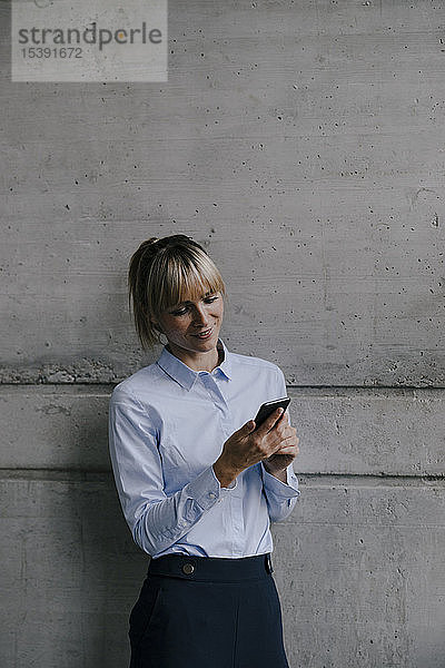 Blonde Geschäftsfrau benutzt Smartphone  liest Nachrichten