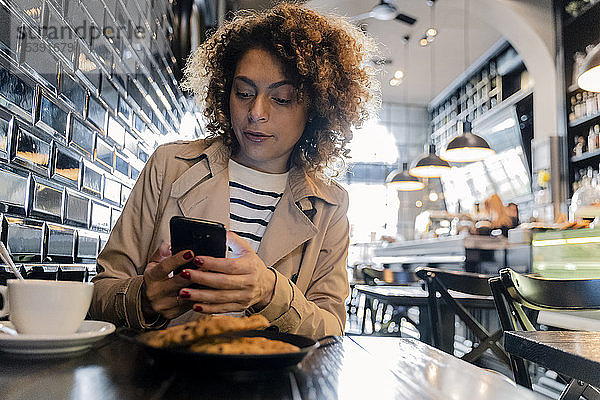 Frau benutzt Mobiltelefon in einem Cafe