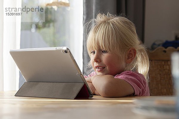 Porträt eines blonden kleinen Mädchens mit digitalem Tablet zu Hause