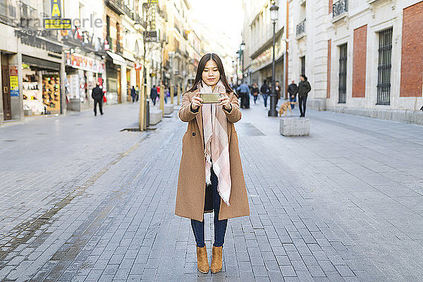 Spanien  Madrid  junge Frau  die in der Stadt mit einem Smartphone fotografiert