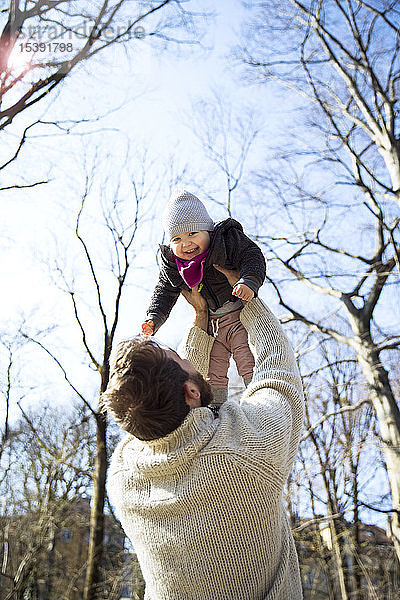 Vater hebt glückliche Tochter im Park hoch